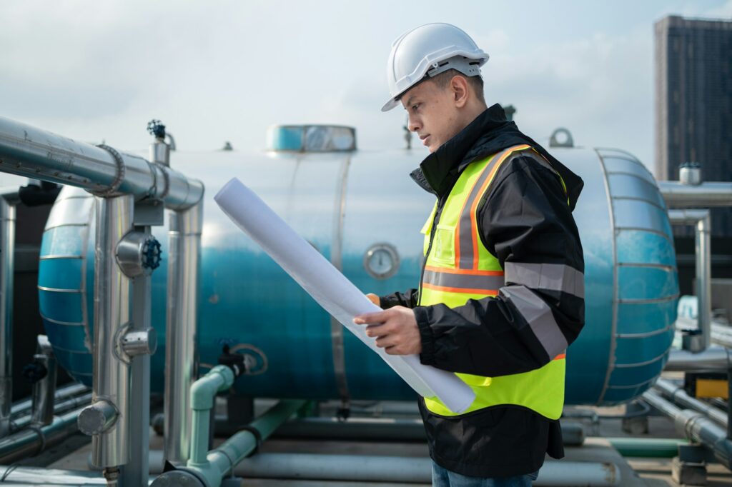 Engineer Analyzing Blueprints at Industrial Pipeline Site