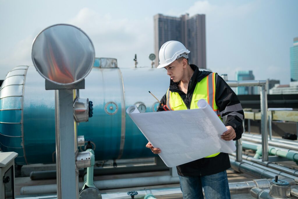 Engineer Analyzing Blueprints at Industrial Pipeline Site